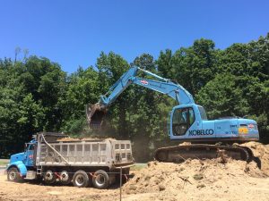 excavator loading spoils into dump truck