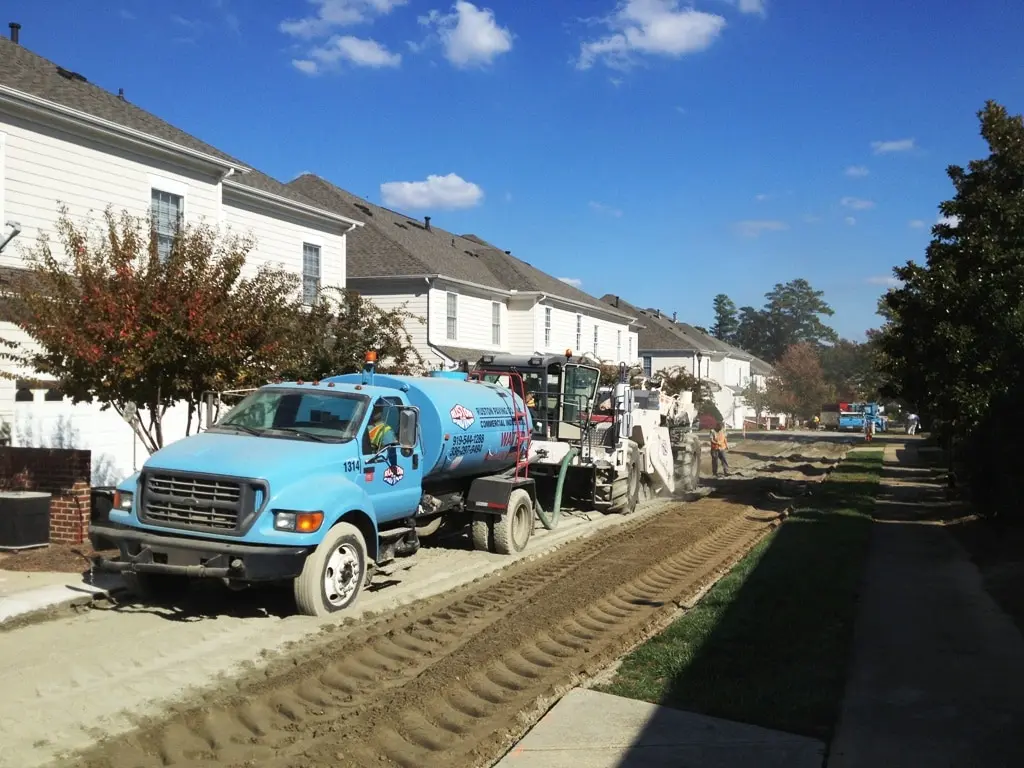 Full-depth reclamation roadway reconstruction with water truck and reclamation equipment processing the existing pavement base